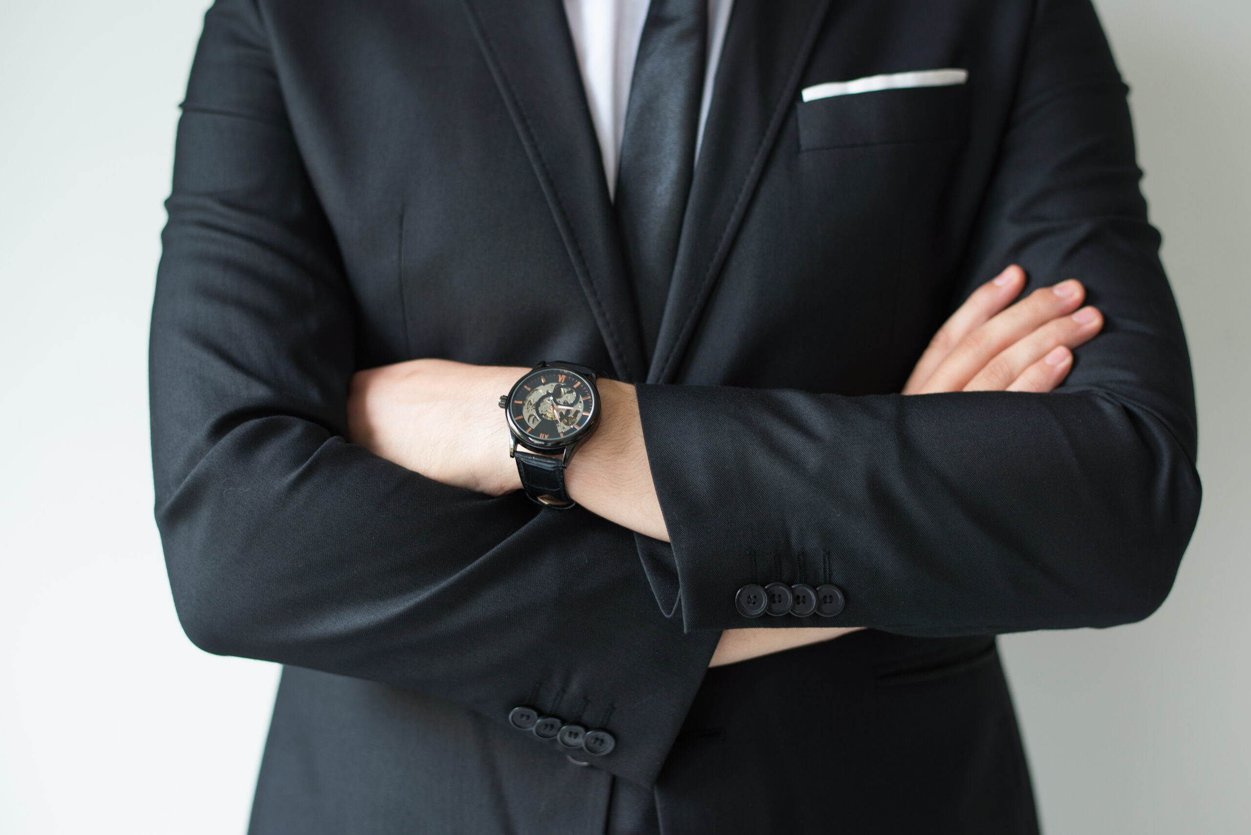 Confident businessman posing with arms crossed. Cropped portrait of business leader in suit with wristwatch. Business success concept